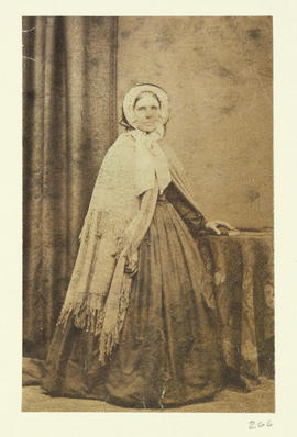 (Elderly woman in fringed shawl, standing)