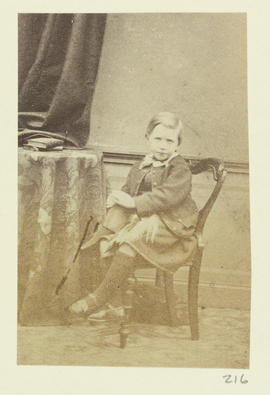 (Boy in kilt seated at a table)