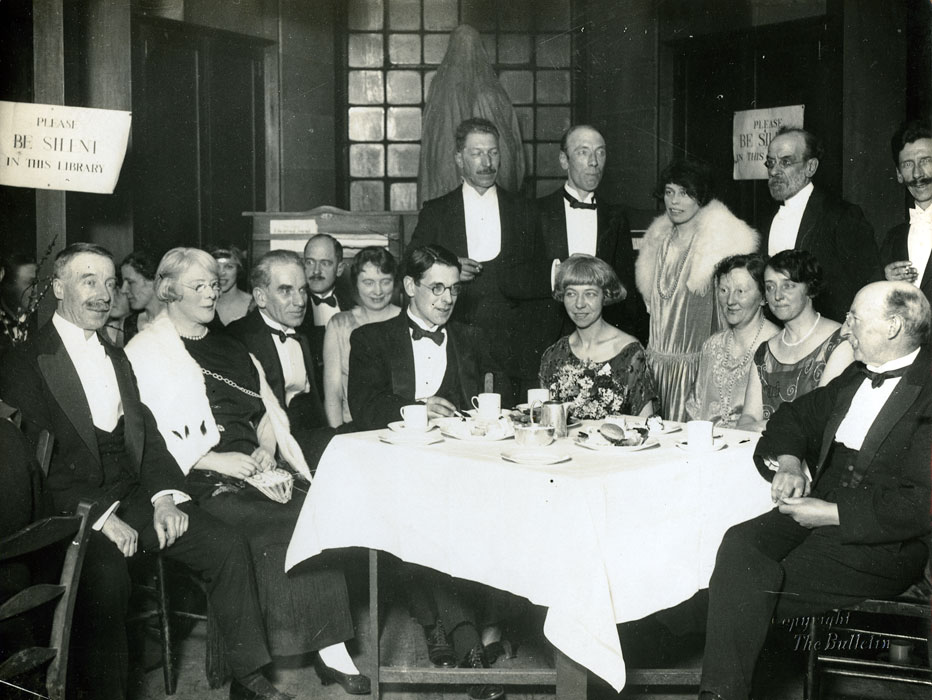 Glasgow School of Art Staff at dinner in the library, featuring A. L, Mrs W. S. Shanks, Allan D. Mainds, Campbell Mackie, Mrs De Courcy Lethwaite Dewar, and P Wylie Davidson (Archive refernce: GSAA/P/1/35)