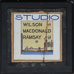 Signage for The Studio, captioned with the names Wilson, Macdonald and Ramsay. Image depicts a studio with yellow walls and blue floors, and a desk full of books and art materials